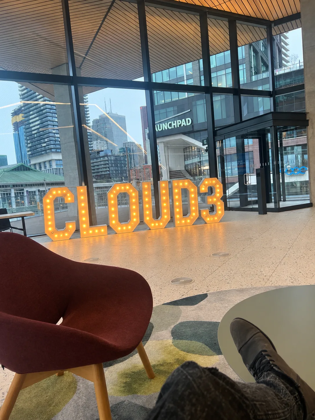 Lit Cloud3 marquee sign in the Toronto workspace lobby with the downtown skyline behind